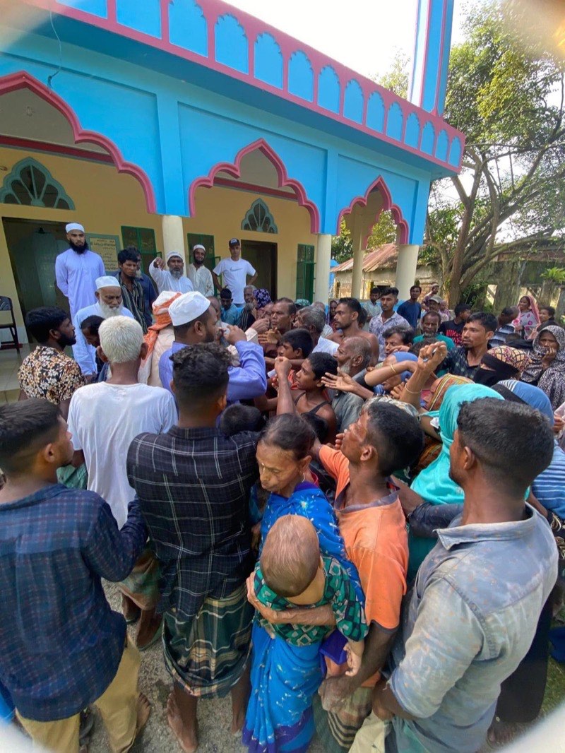Villagers gathered outside a village mosque to receive food parcels